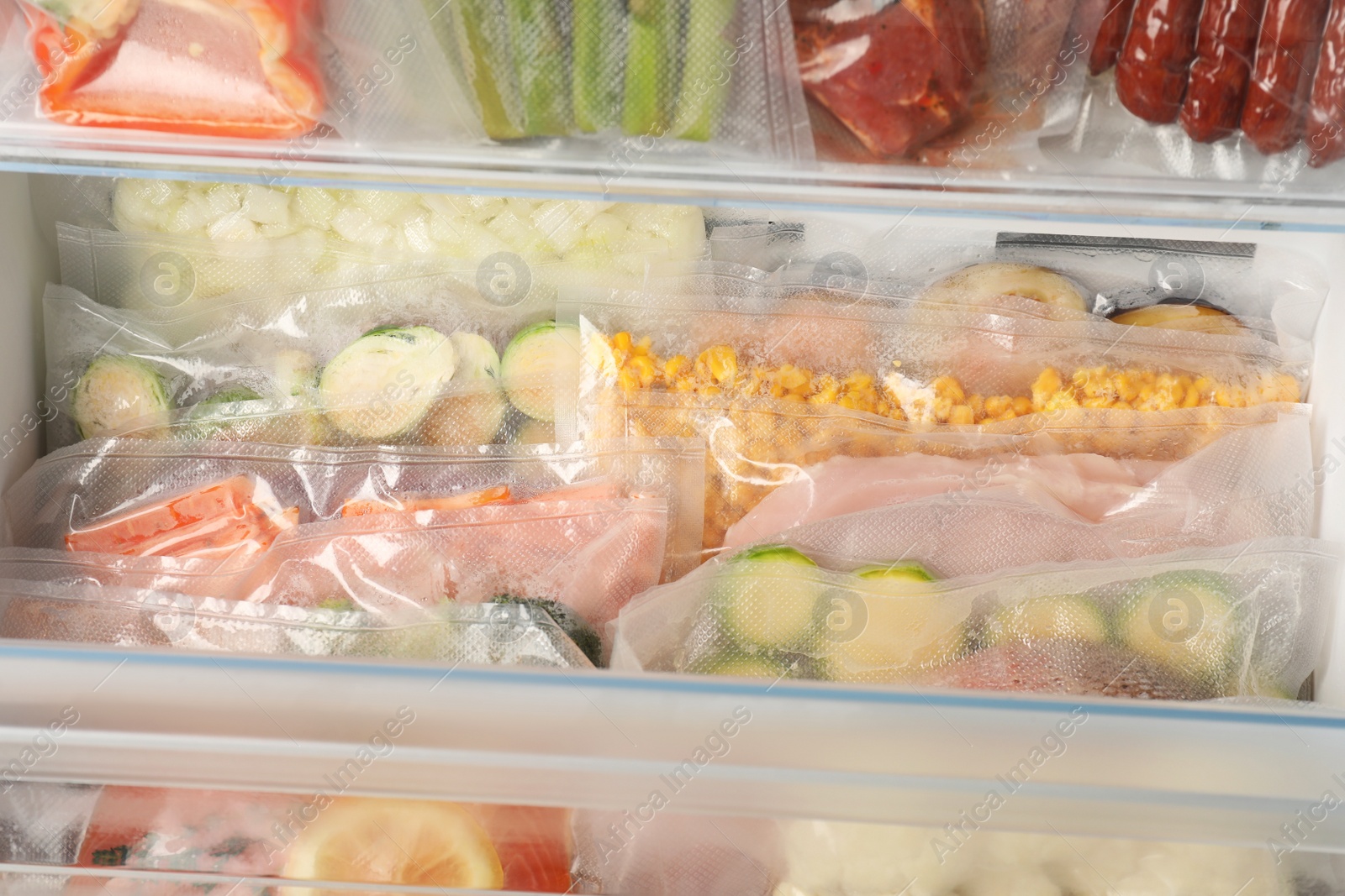 Photo of Vacuum bags with different products in fridge, closeup. Food storage