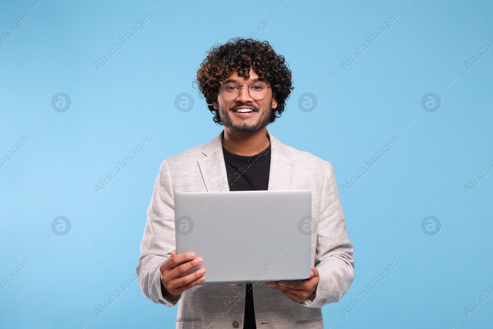 Photo of Smiling man with laptop on light blue background