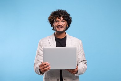 Smiling man with laptop on light blue background