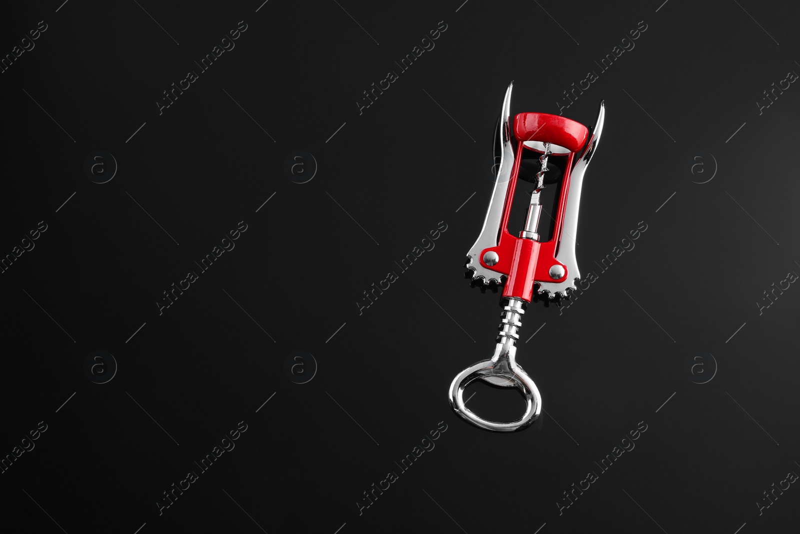 Photo of One wing corkscrew on black table, top view. Space for text