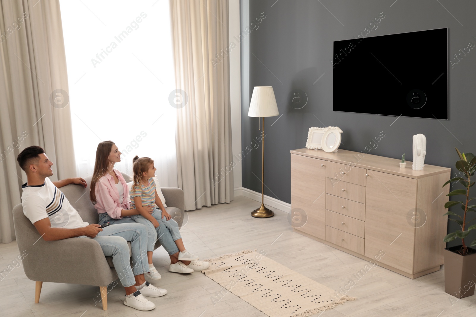 Photo of Happy family watching TV on sofa at home