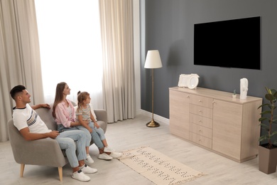 Photo of Happy family watching TV on sofa at home