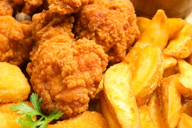 Photo of Tasty deep fried chicken pieces with garnish as background, closeup