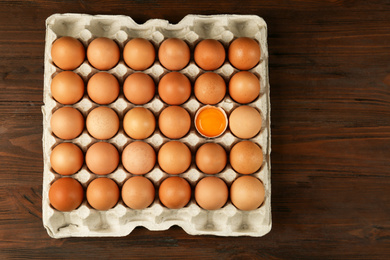 Photo of Raw chicken eggs on wooden table, top view
