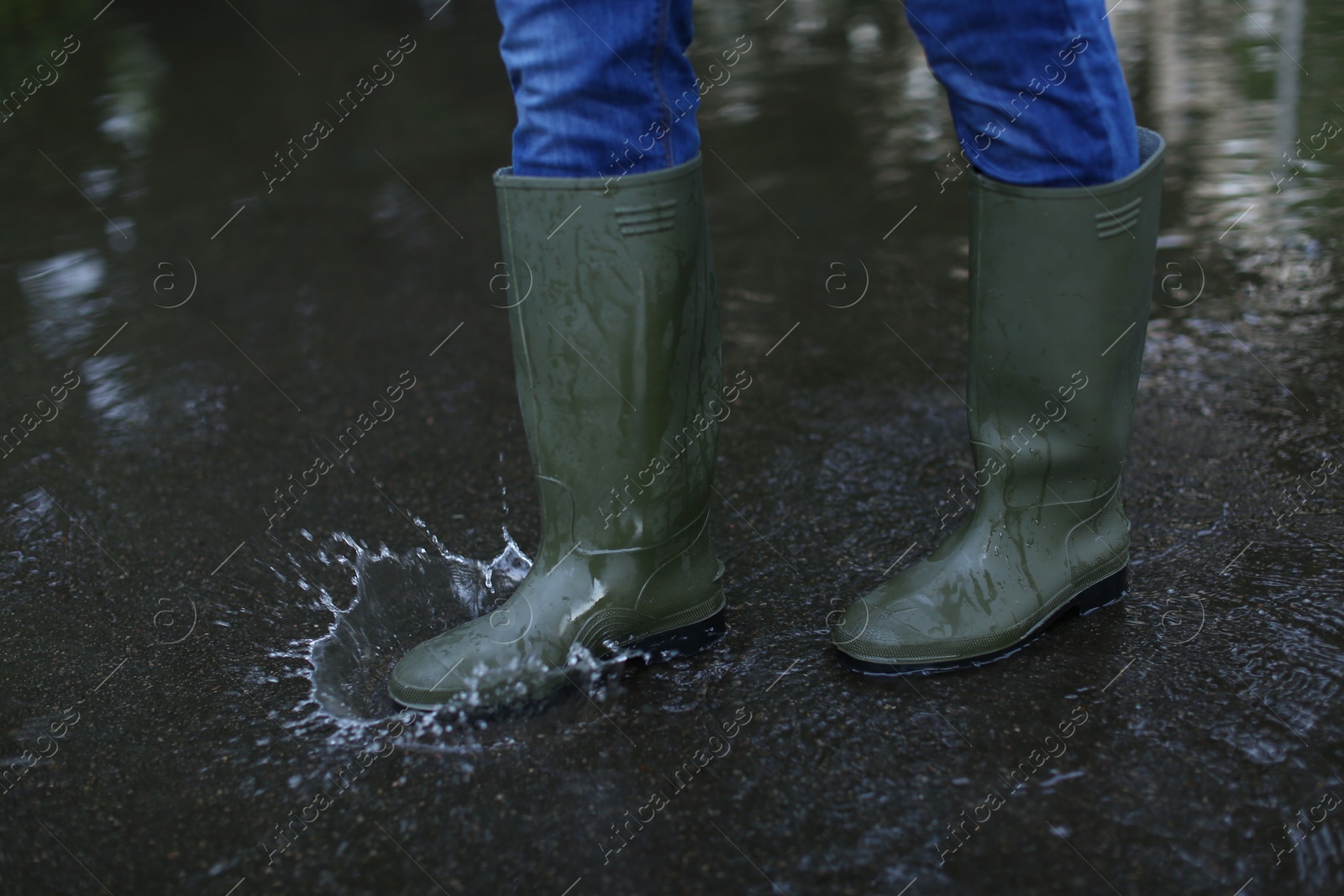 Image of Man in rubber boots walking on wet street after rain, closeup