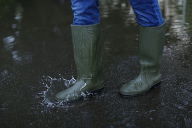 Image of Man in rubber boots walking on wet street after rain, closeup