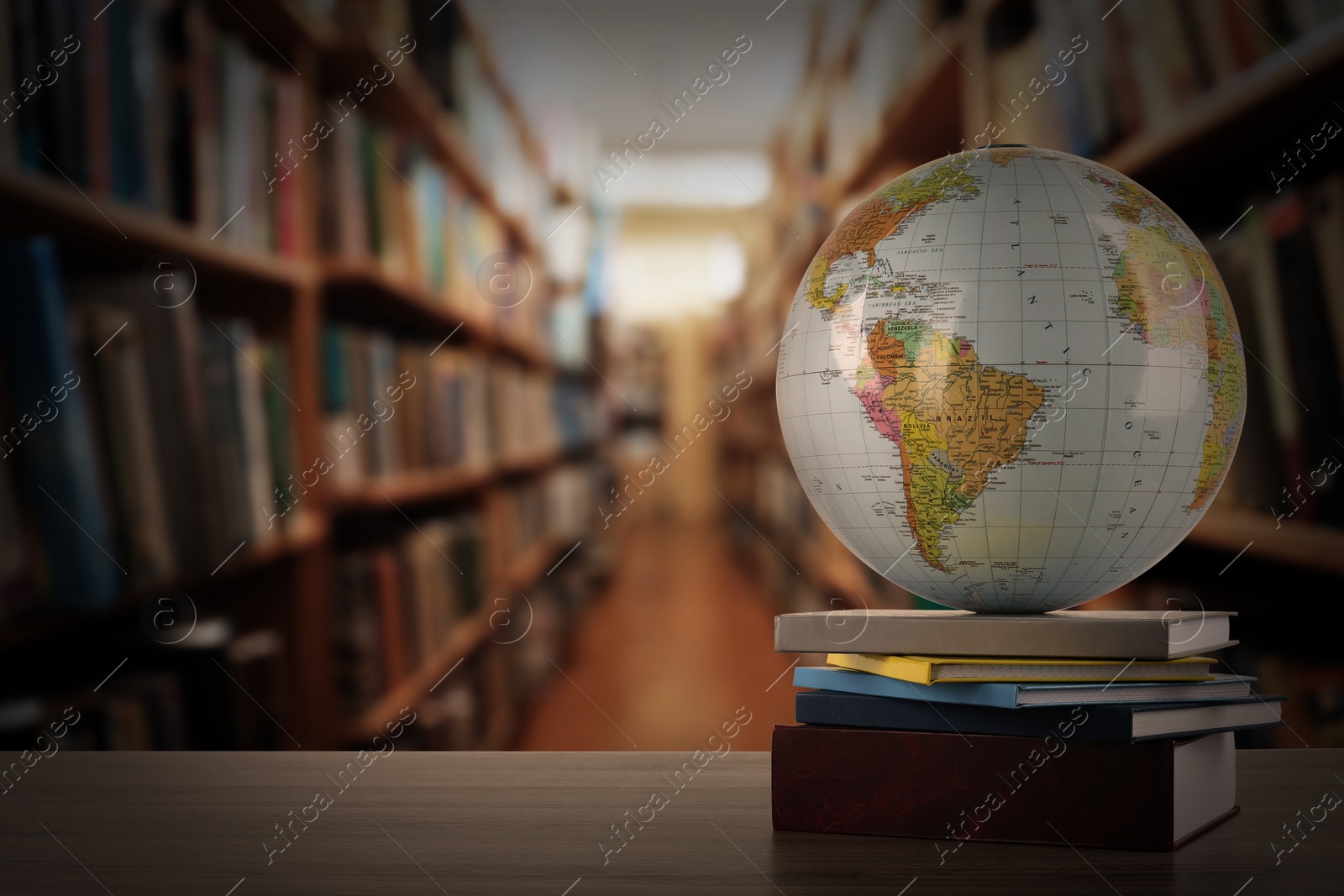 Image of Globe and books on wooden table in library. Space for text