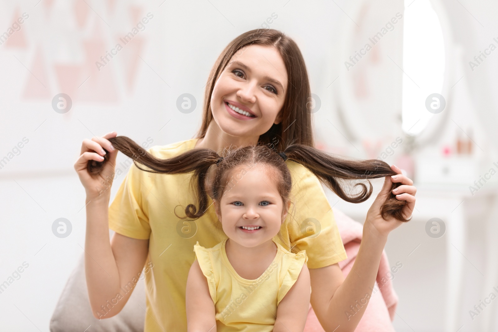 Photo of Young mother with little daughter having fun at home