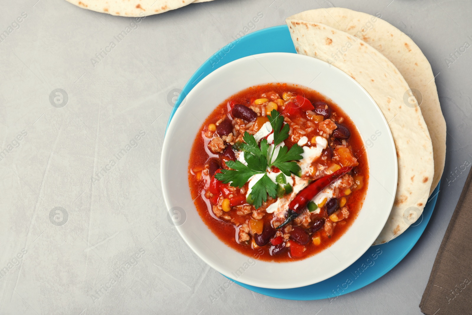 Photo of Tasty chili con carne served on gray table, flat lay