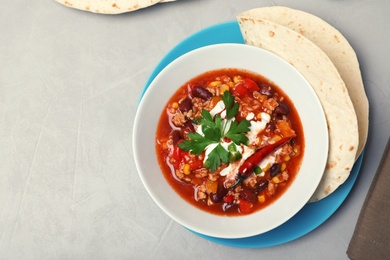 Tasty chili con carne served on gray table, flat lay