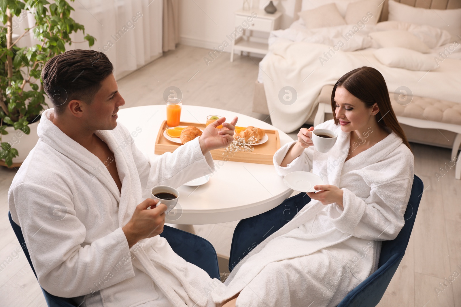 Photo of Happy couple in bathrobes having breakfast at home