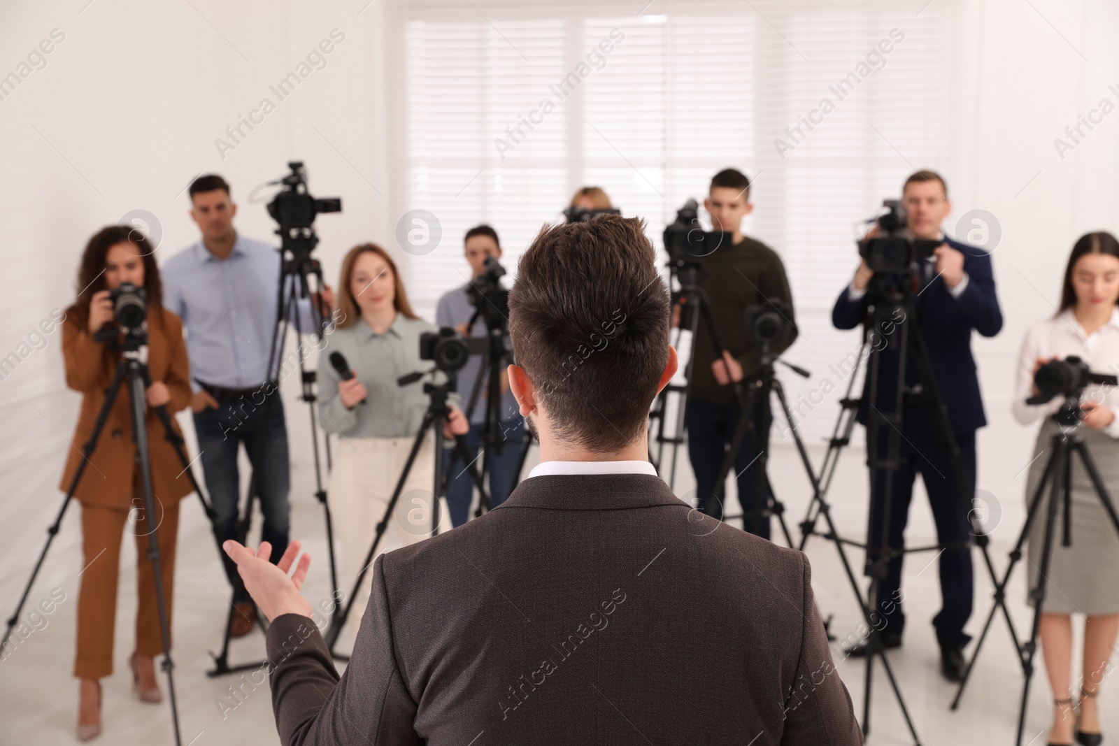 Photo of Business man talking to group of journalists indoors, back view