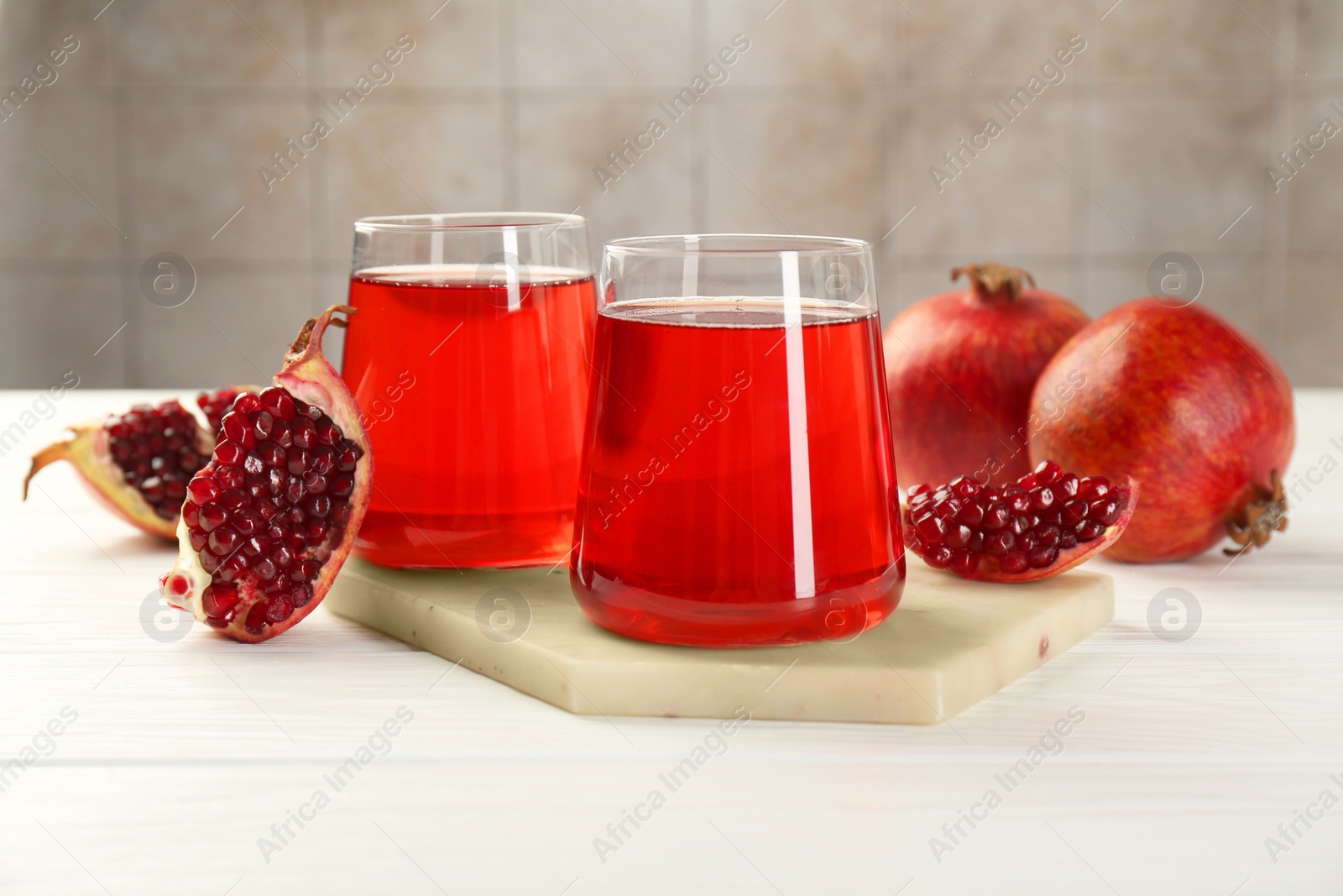 Photo of Tasty pomegranate juice in glasses and fresh fruits on white wooden table