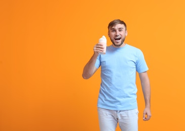 Young man with glass of delicious milk shake on color background