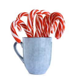 Photo of Grey cup with sweet Christmas candy canes isolated on white