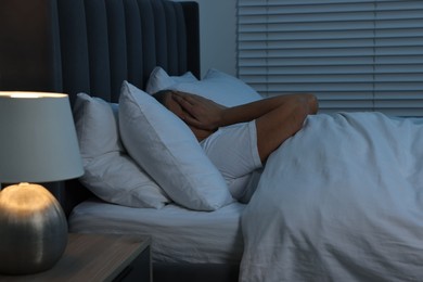 Photo of Woman suffering from headache in bed at night