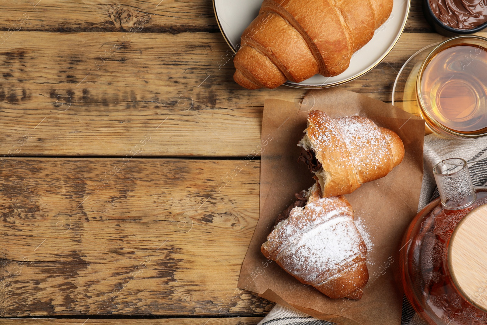 Photo of Flat lay composition with tasty croissants and tea on wooden table. Space for text