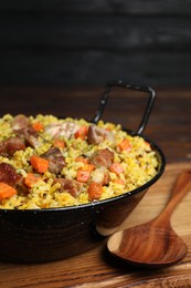 Delicious pilaf with meat and carrot served on wooden table, closeup