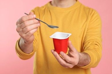 Photo of Man with delicious yogurt and spoon on pink background, closeup