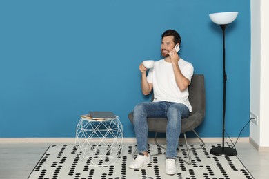 Photo of Man talking on smartphone in armchair, space for text. Stylish room interior