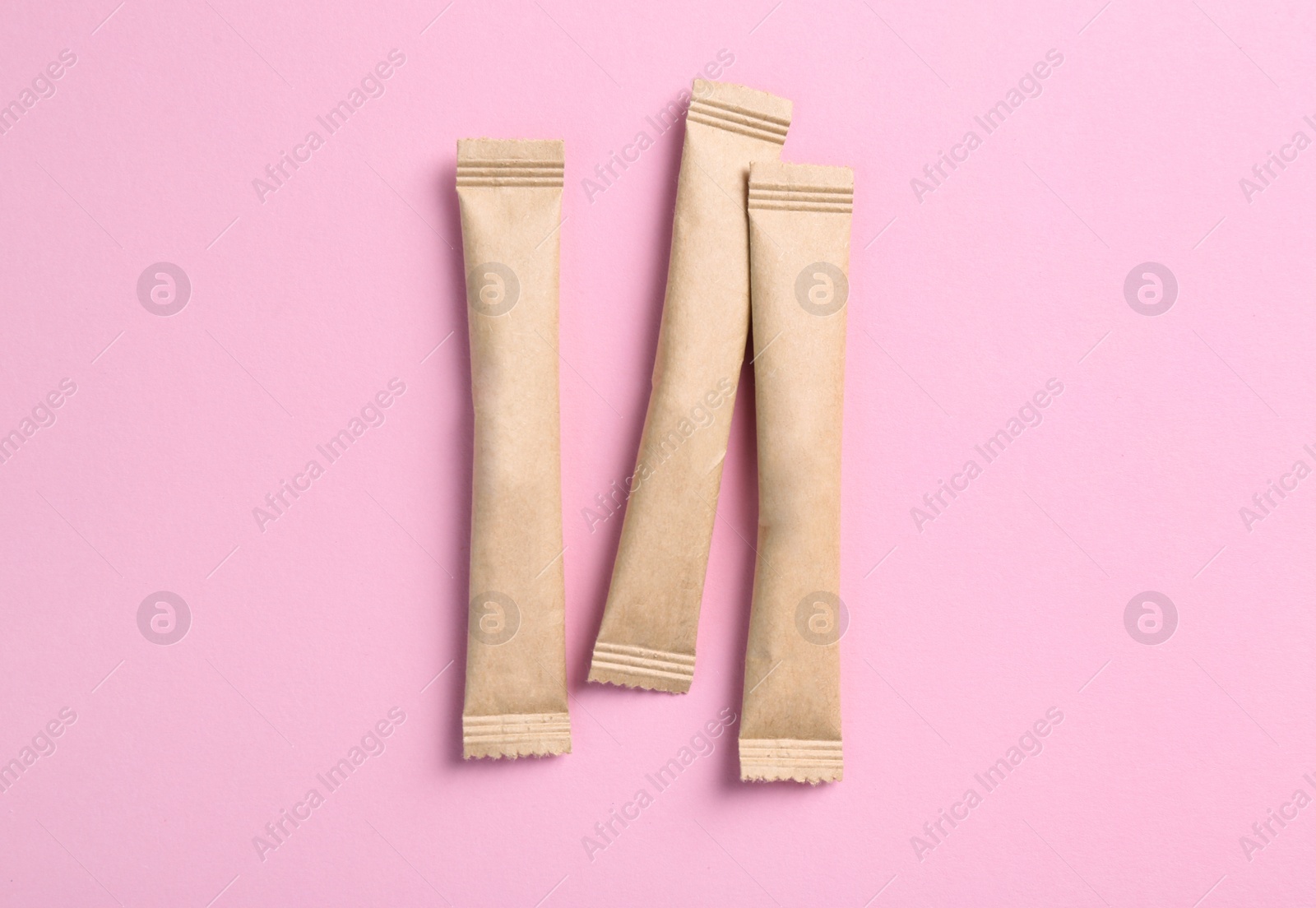 Photo of Beige sticks of sugar on pink background, flat lay