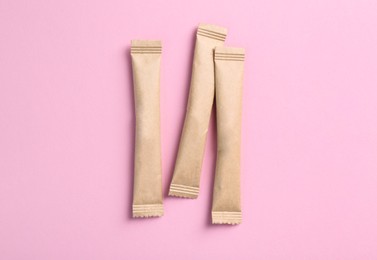 Beige sticks of sugar on pink background, flat lay