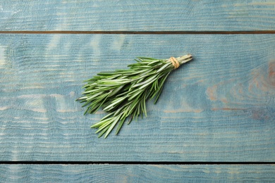 Photo of Bunch of fresh rosemary on blue wooden table, above view