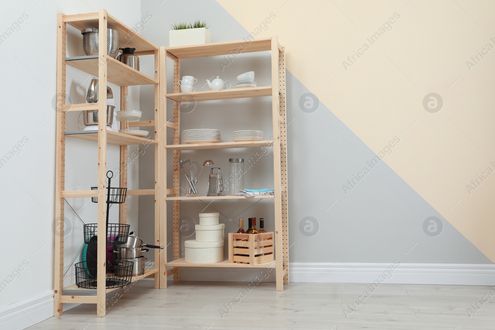 Photo of Wooden shelving units with kitchenware near color wall, space for text. Stylish room interior