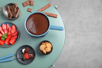 Photo of Table with chocolate fondue on grey floor, top view. Space for text