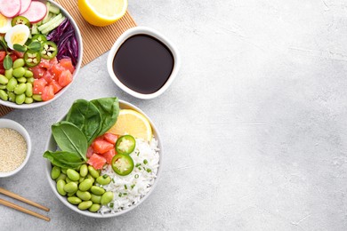 Photo of Poke bowl with salmon, edamame beans and rice on light grey table, flat lay. Space for text