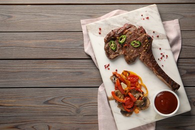 Delicious fried beef meat served with vegetables and sauce on wooden table, top view. Space for text