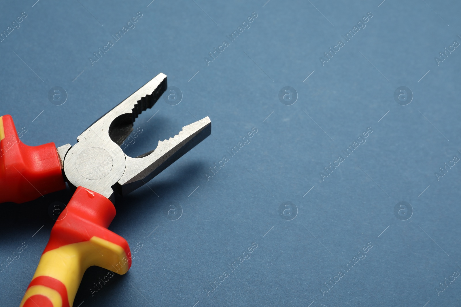 Photo of Combination pliers on blue background, closeup. Space for text