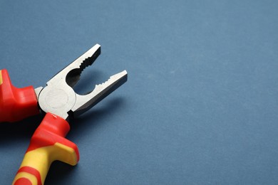 Combination pliers on blue background, closeup. Space for text