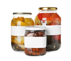 Photo of Jars of pickled vegetables with blank labels on white background