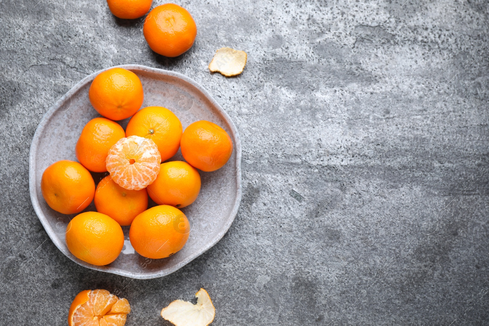 Photo of Fresh ripe tangerines and peel on grey table, flat lay. Space for text
