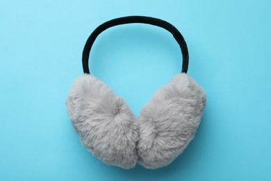 Stylish warm earmuffs on light blue background, top view