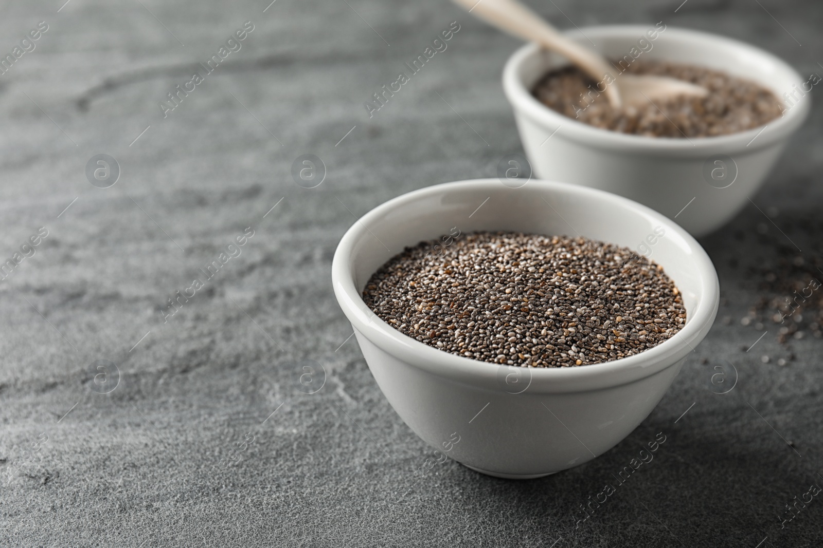 Photo of Bowl with chia seeds on grey background, space for text