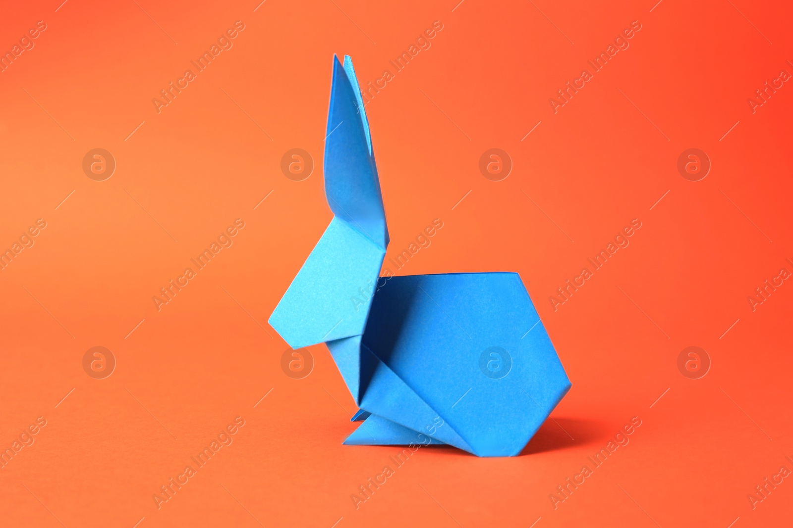 Photo of Origami art. Beautiful paper rabbit on orange background