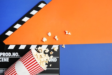 Photo of Flat lay composition with popcorn, cinema clapperboard and space for text on color background