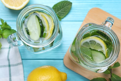 Photo of Refreshing water with cucumber, lemon and mint on light blue wooden table, flat lay