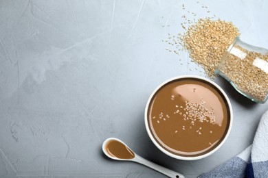 Tasty sesame paste and seeds on light grey table, flat lay. Space for text