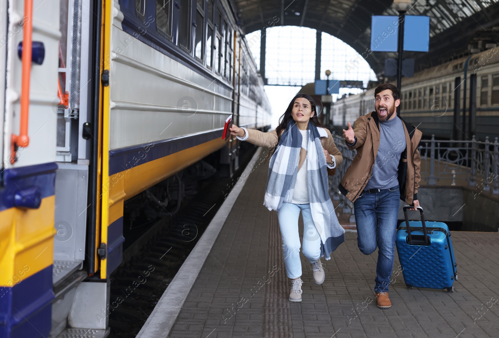 Photo of Being late. Worried couple with suitcase running towards train at station, space for text