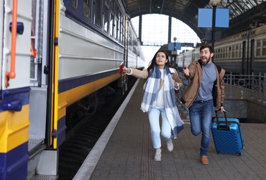 Being late. Worried couple with suitcase running towards train at station, space for text