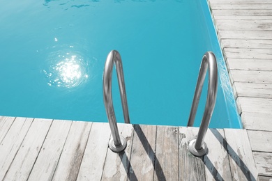 Modern swimming pool with ladder at resort