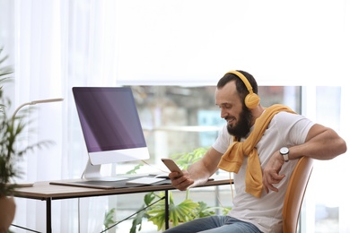 Photo of Mature man with headphones and computer in home office