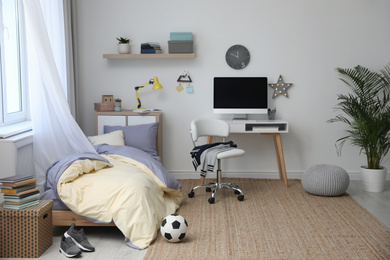 Stylish teenager's room interior with comfortable bed and workplace