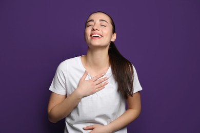 Photo of Beautiful young woman laughing on purple background. Funny joke