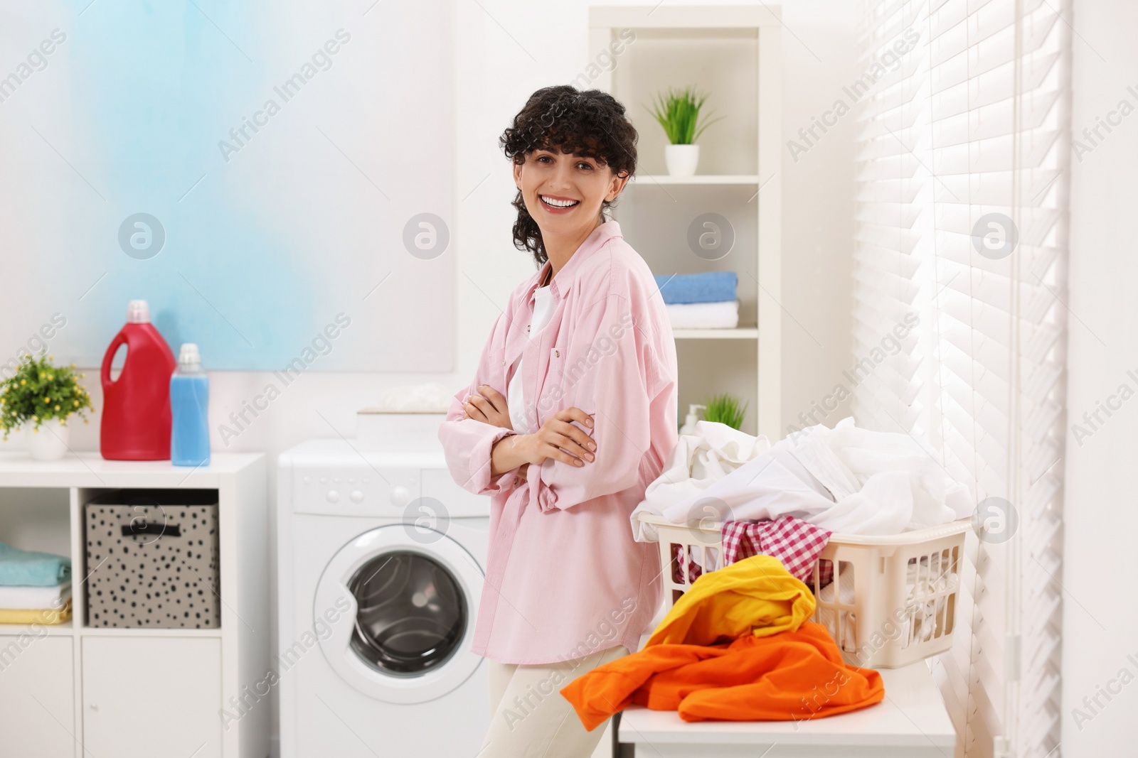 Photo of Happy woman with laundry near window indoors