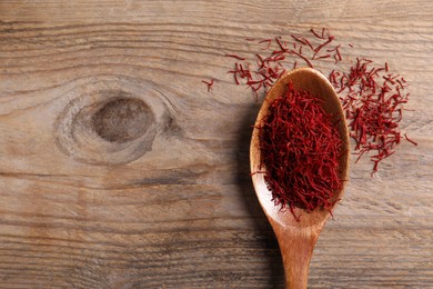 Aromatic saffron and spoon on wooden table, top view. Space for text