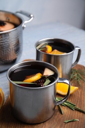 Photo of Tasty mulled wine with spices in mugs on wooden table